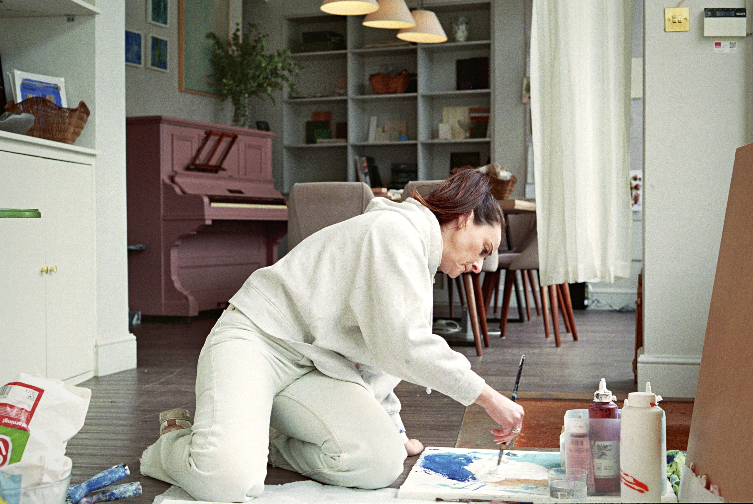 Artist painting in profile with studio visible behind