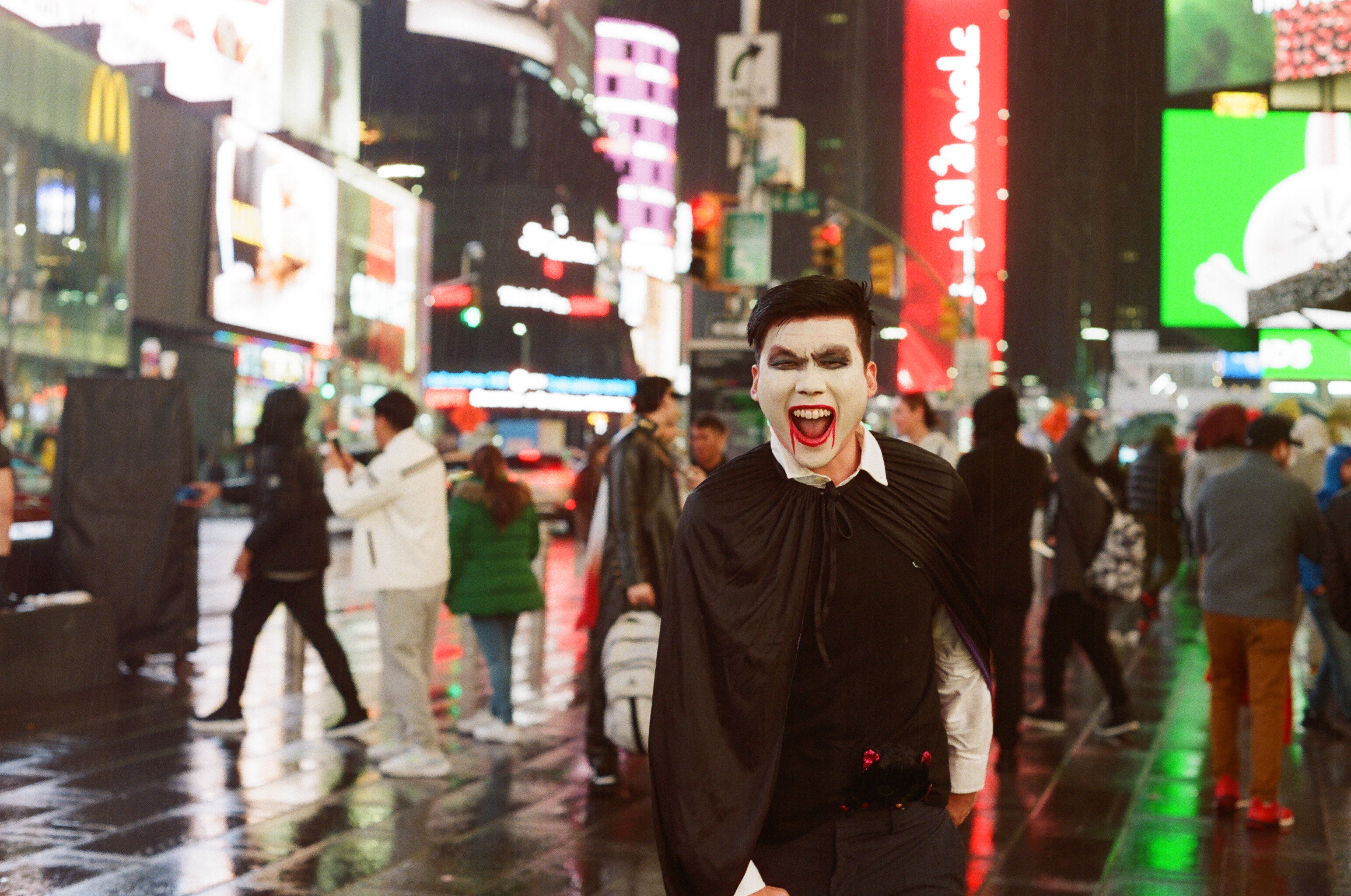 Halloween vampire face paint laughing Times Square neon rain New York — candid event film