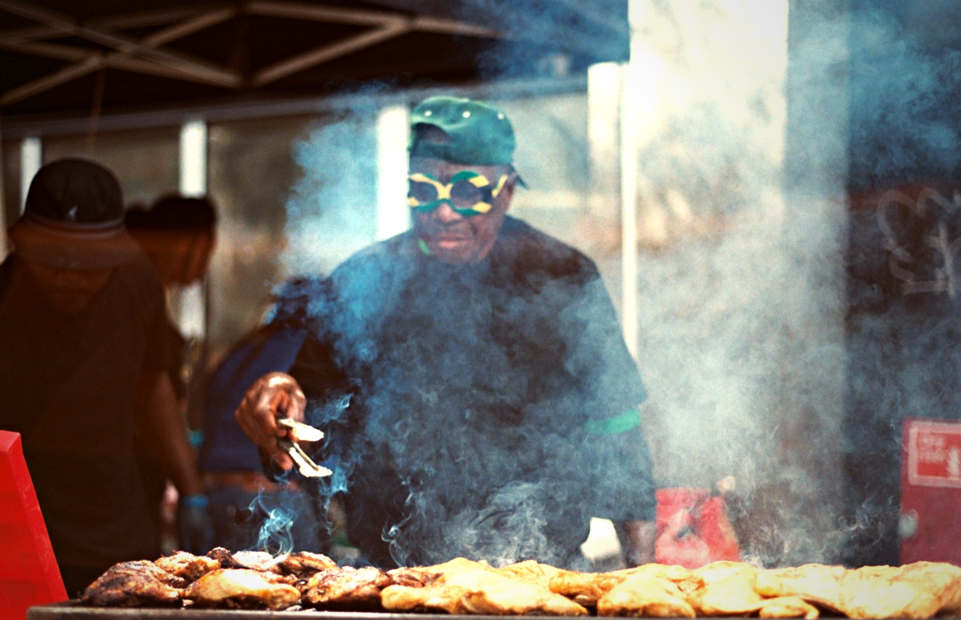 Jerk chicken grill master smoke Jamaican flag glasses Notting Hill Carnival — food culture film photography