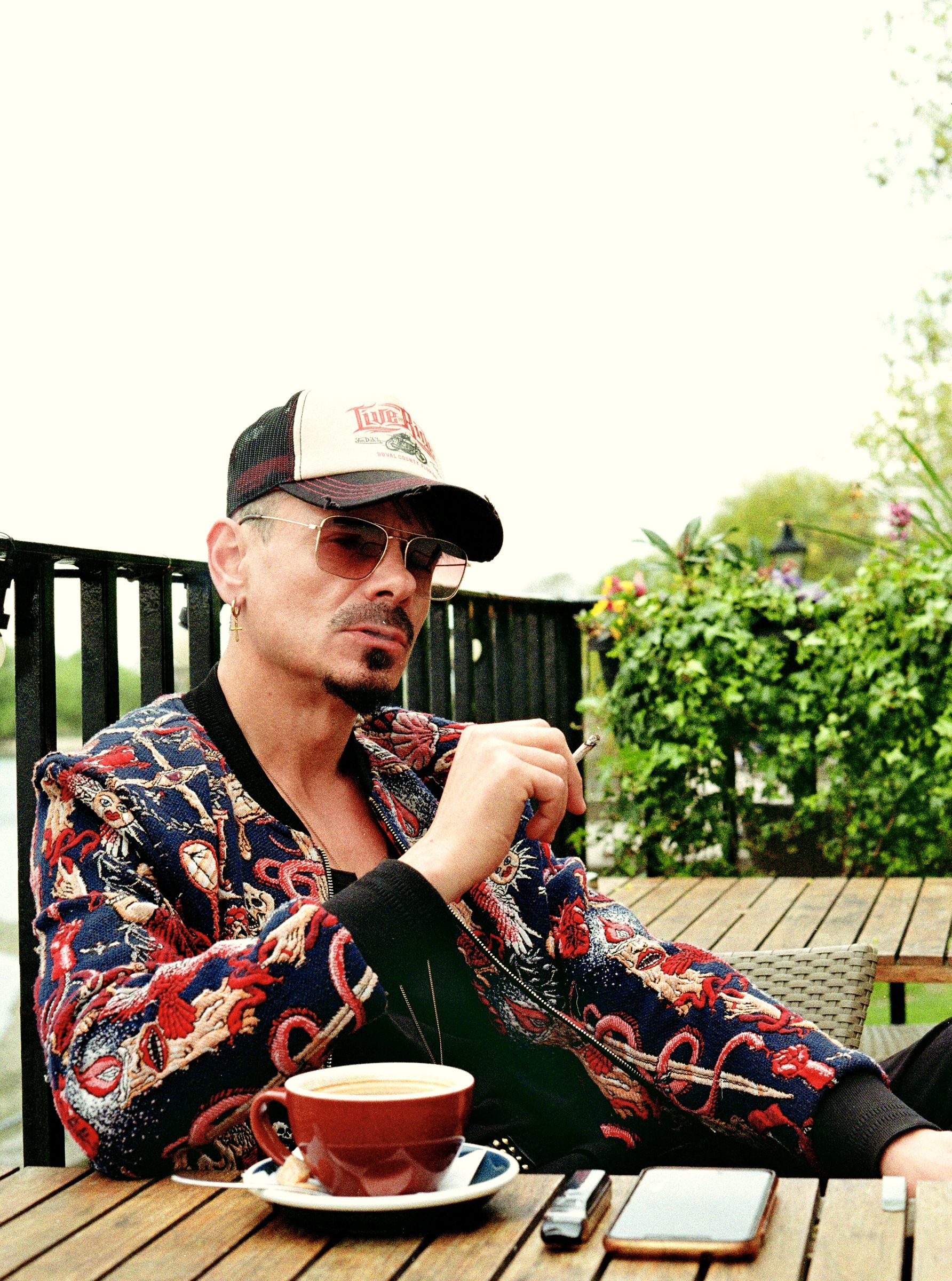 Man with coffee embroidered jacket London — lifestyle portrait