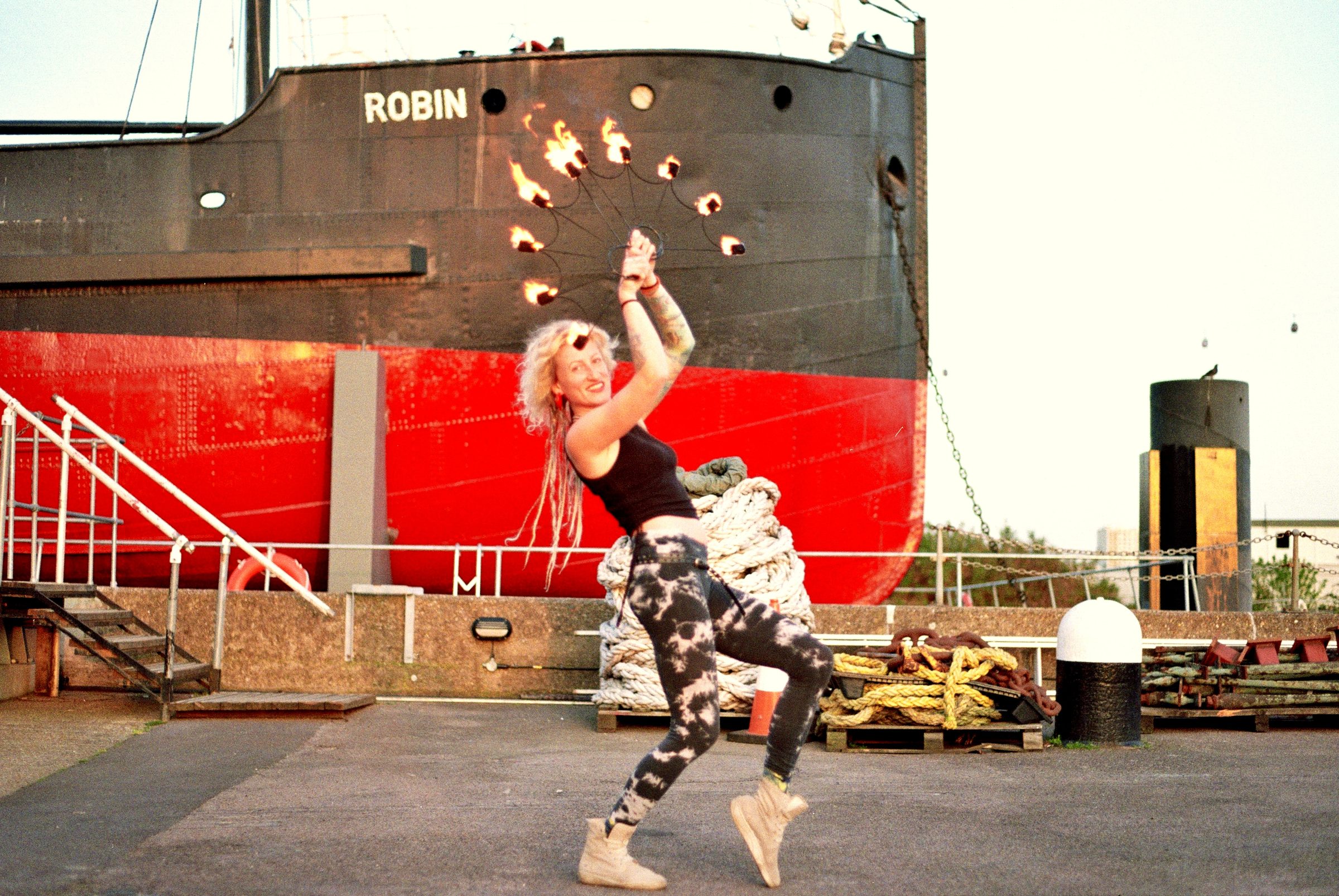 Fire artist performing at Trinity Buoy Wharf with ship Robin behind — London creative portrait