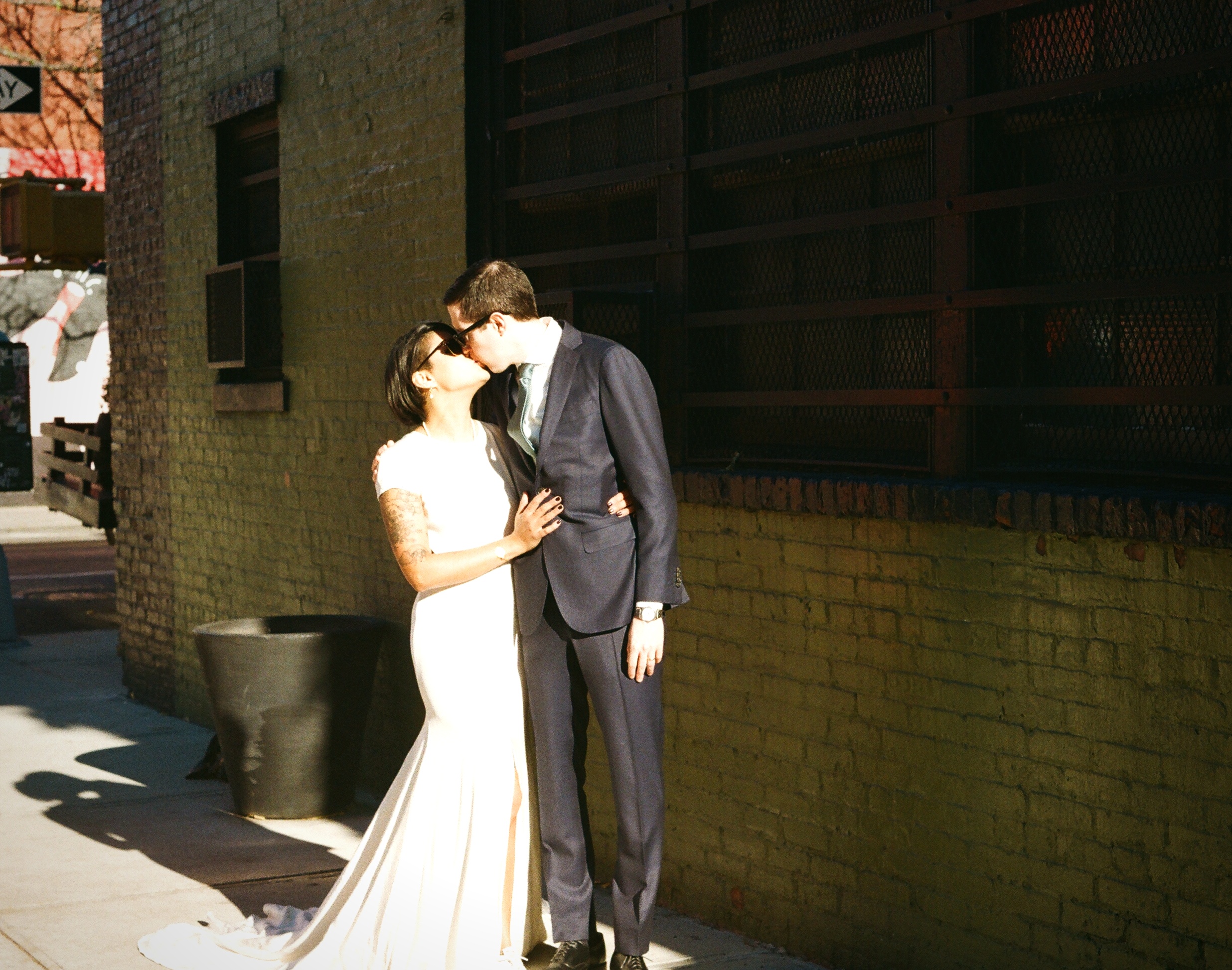 Couple kissing against industrial brick wall New York — film wedding photography
