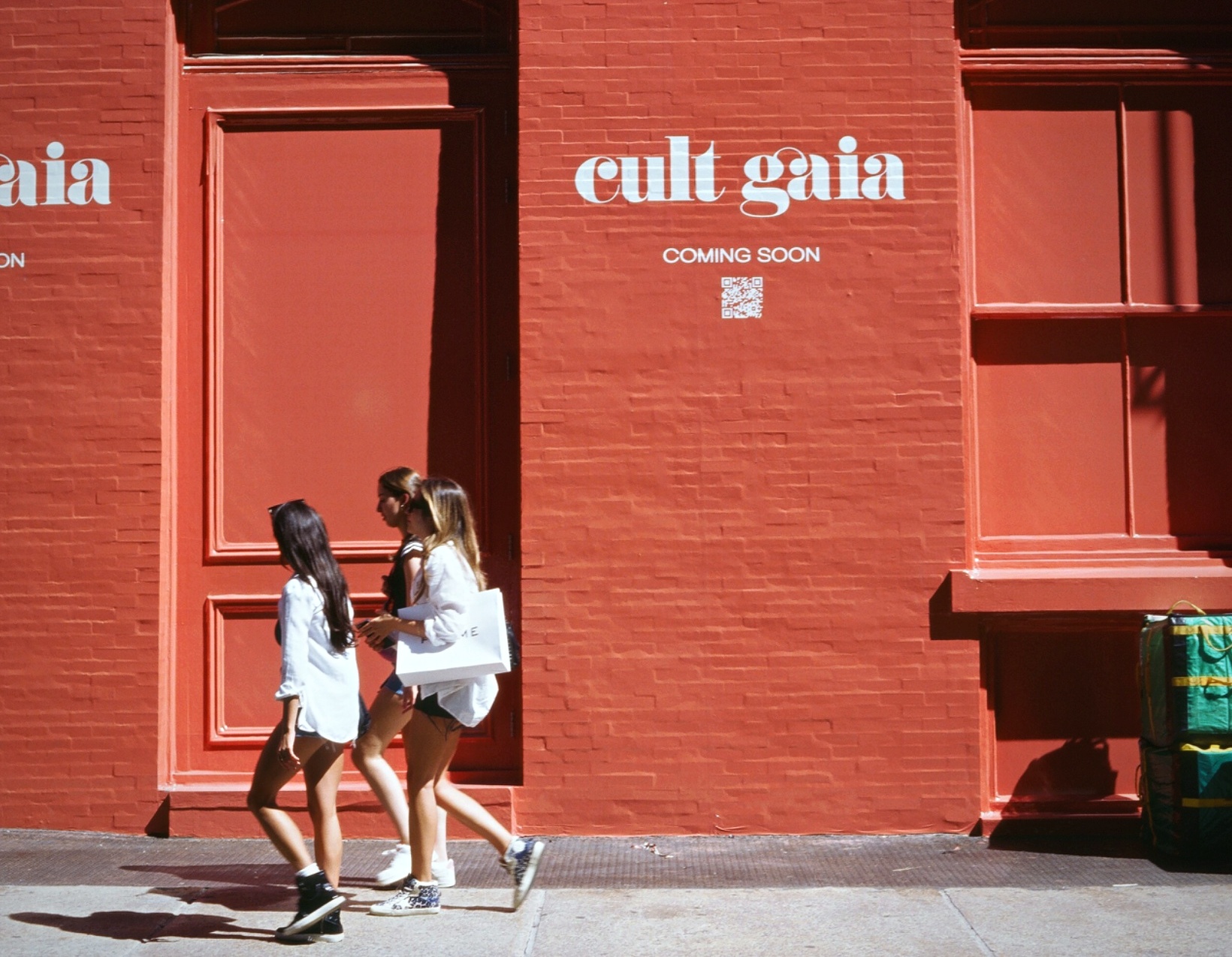 Friends walking past red Cult Gaia storefront New York — street photography on film