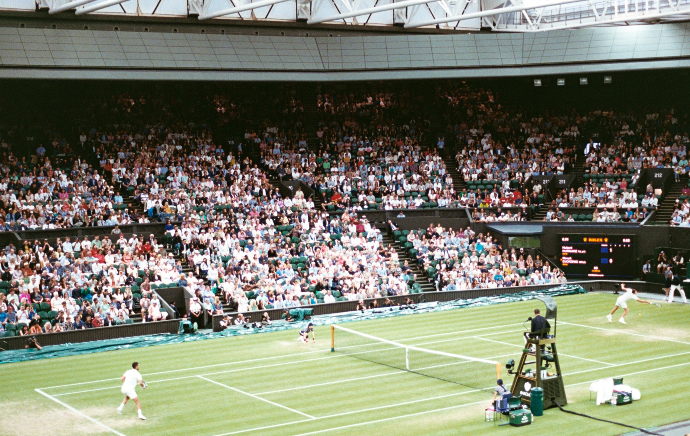Centre Court during a match, the grass striped and bright beneath a full house.