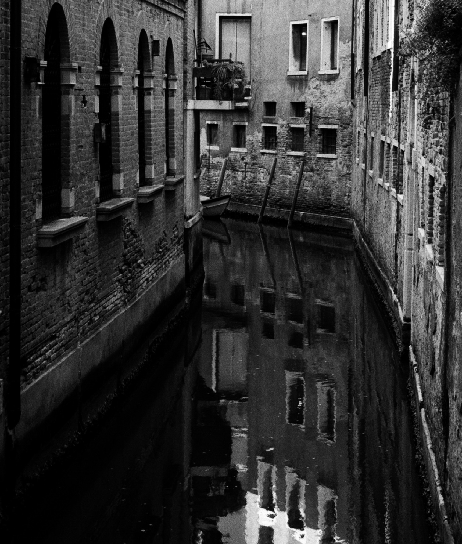 A closer view of the same canal, the windows and their reflections doubled in the water.