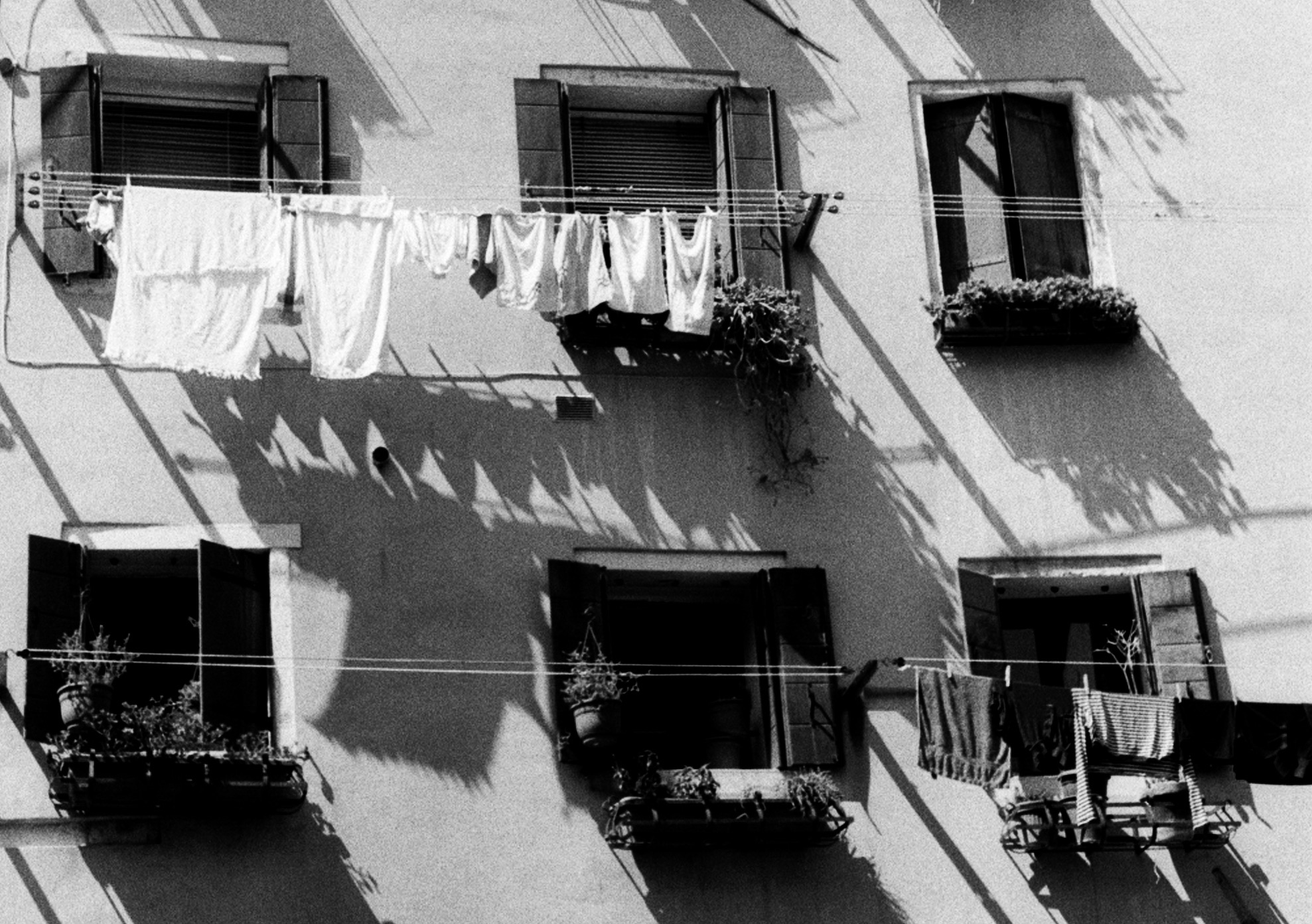 White sheets on a washing line, reduced to flat geometric shapes against a sunlit wall.